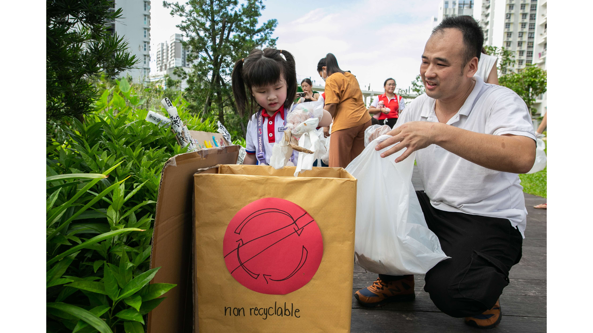 young girl puts trash into a box labelled non recyclable